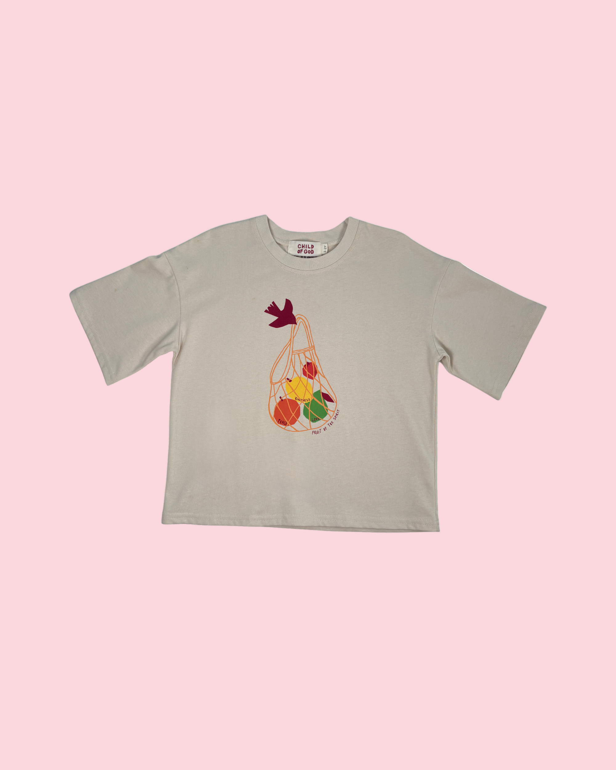 Beige t-shirt with a graphic of a bag of fruits and vegetables on a white background