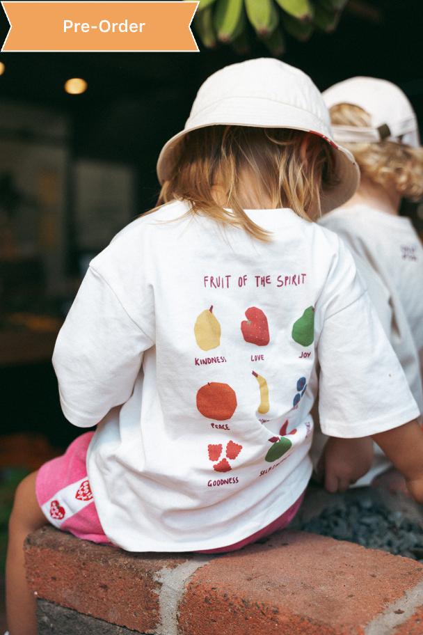 Two children wearing white t-shirts with colorful fruit illustrations and text.