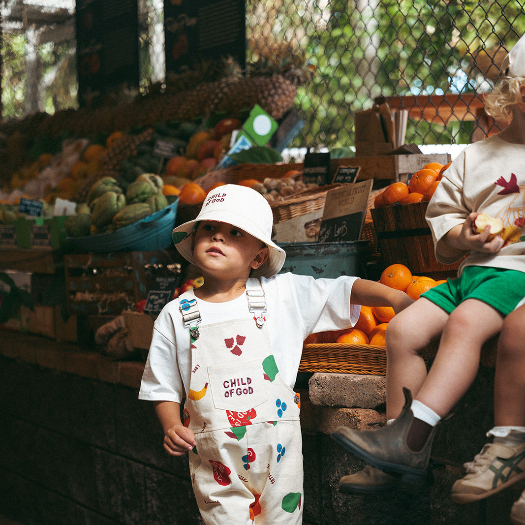 Two children at a farmers market with produce in the background
