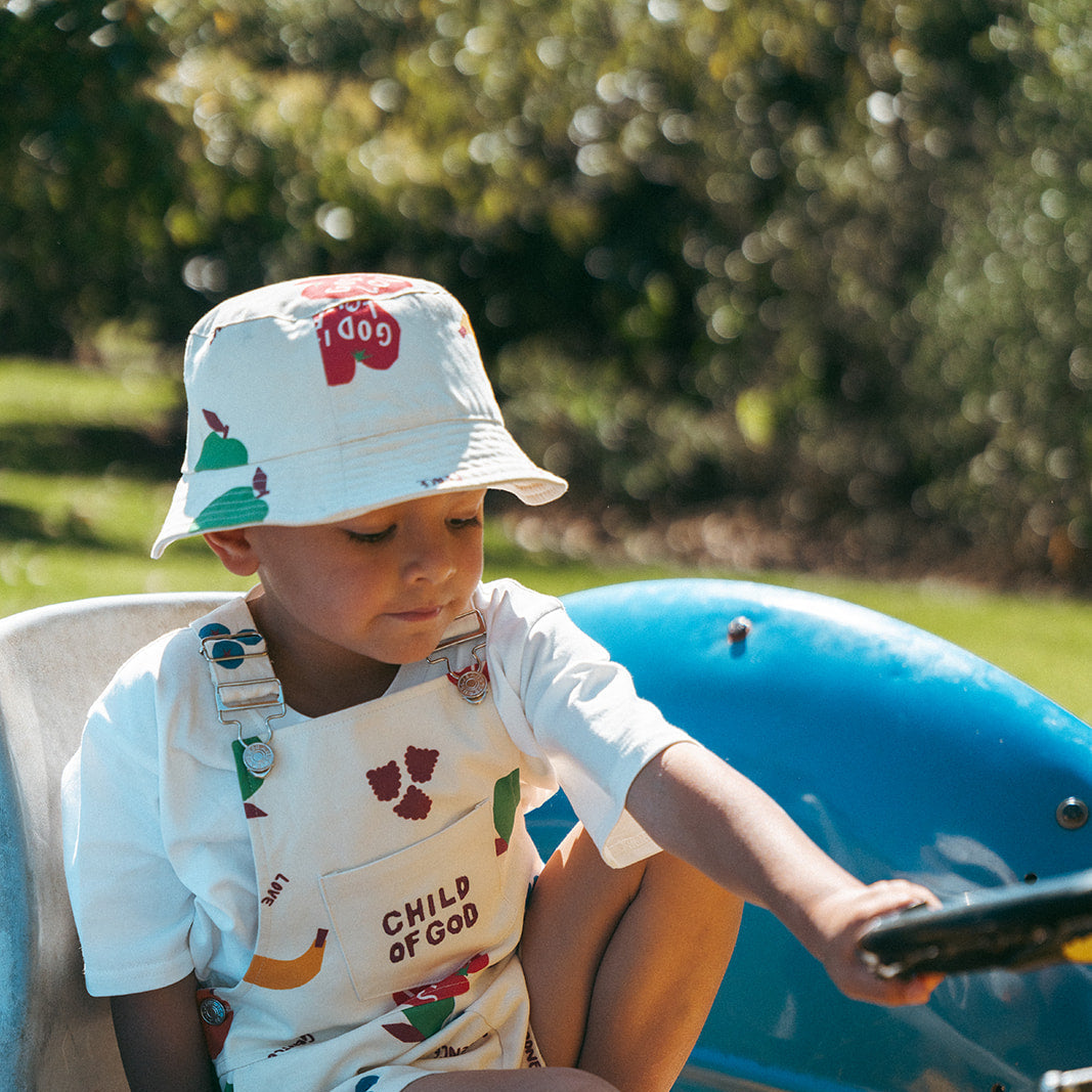 Child sitting on a small blue vehicle outdoors with greenery in the background